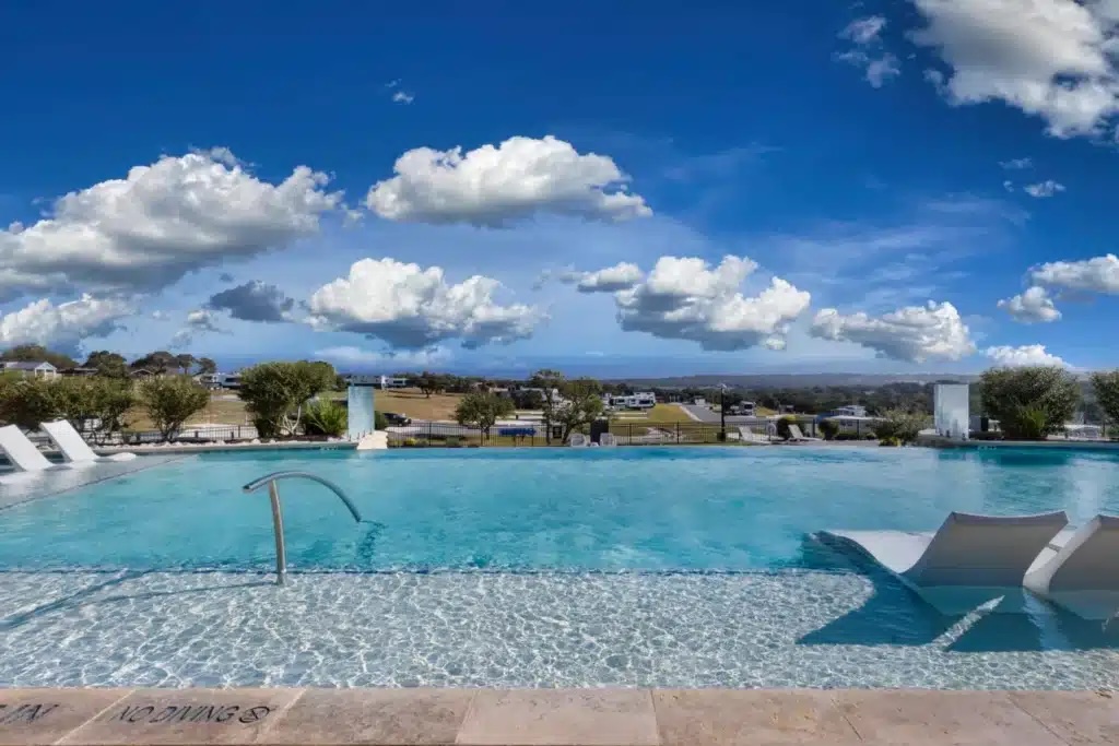 The resort pool with lounge chairs and a Hill Country view